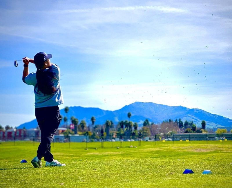 Golfer finishing a swing on the range, Mt. Diablo in the background